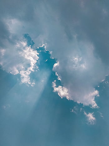 Stunning cumulus clouds in a vibrant blue sky with sunrays streaming through for a serene atmosphere. HD phone wallpaper