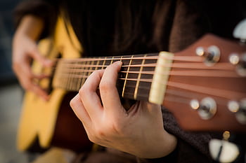 Close view of fingers strumming an acoustic guitar, capturing the essence of music creation. HD wallpaper