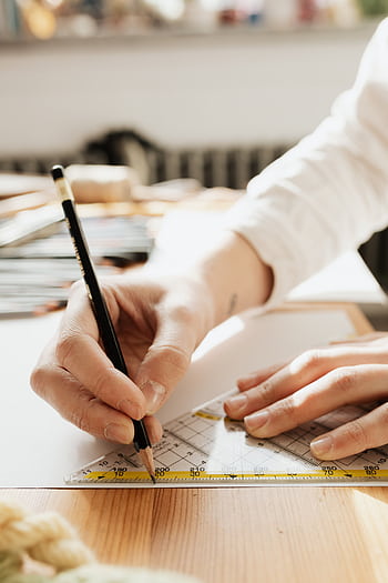 Close-up of a person sketching with a pencil and ruler, capturing precision and artistry. HD phone wallpaper