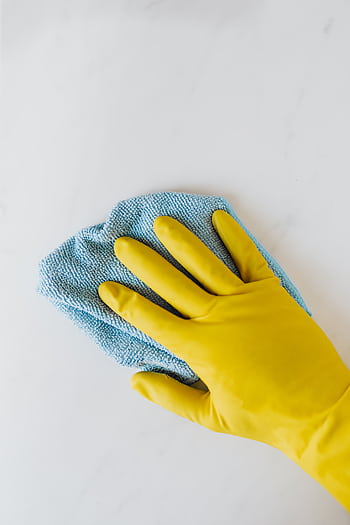 Yellow gloved hand wiping surface with blue cloth, concept of cleaning and hygiene. HD phone wallpaper