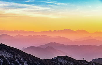 Colorful sunrise over misty mountains in Altmünster, Austria with a lone hiker silhouette. HD wallpaper
