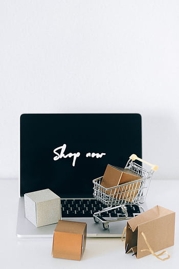 Minimalist online shopping setup with laptop, cart, and packages symbolizing e-commerce. HD phone wallpaper