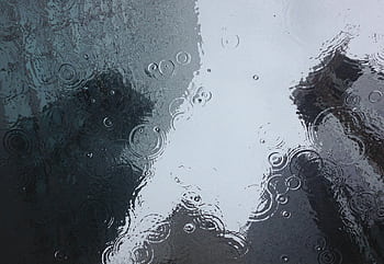 Raindrops create ripples on a window, reflecting an urban backdrop. HD wallpaper