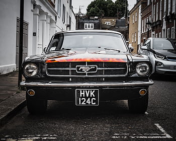 Front view of a vintage Ford Mustang parked on a London street, showcasing iconic design. HD wallpaper