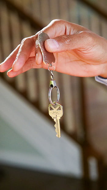 Close-up of a hand holding a key, symbolizing new homeownership or rental. HD phone wallpaper