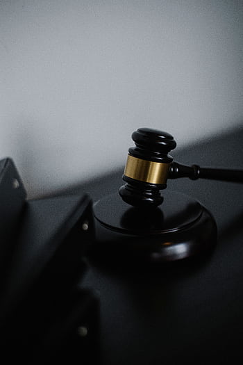 A close-up view of a judge's gavel on a desk, symbolizing justice and law. HD phone wallpaper
