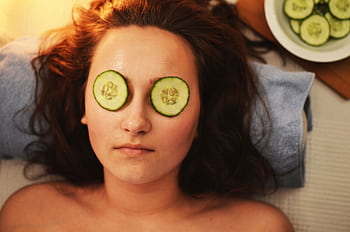 Woman enjoying a relaxing cucumber facial treatment at a spa for skin care and rejuvenation. HD wallpaper