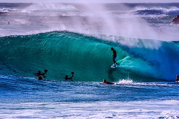 Dynamic surfing action on a bright ocean wave during a sunny day. HD wallpaper