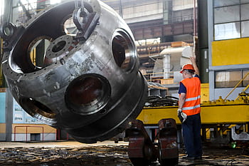 Worker in safety gear operating machinery inside an industrial plant. HD wallpaper