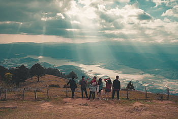 A group of people admire the beautiful valley and dramatic sky, perfect for travel and nature concepts. HD wallpaper