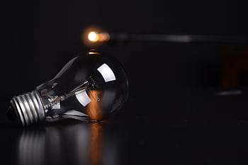 Detailed shot of a reflective light bulb on a dark background, showcasing lighting and reflections. HD wallpaper
