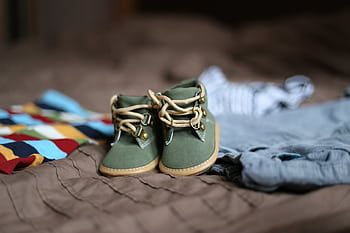 Adorable green baby booties surrounded by colorful clothes, perfect for infant fashion. HD wallpaper