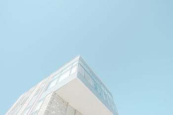 A low-angle shot of a modern building with a glass facade against a bright blue sky in London, Canada. HD wallpaper