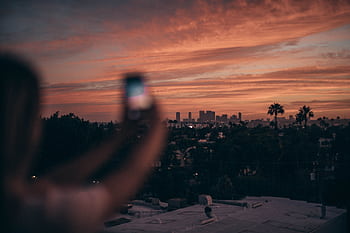 A person graphing the Los Angeles skyline during a vibrant sunset. HD wallpaper