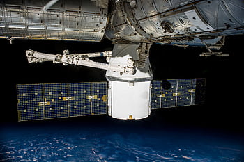 A satellite with solar panels orbiting Earth, capturing the vast universe. HD wallpaper