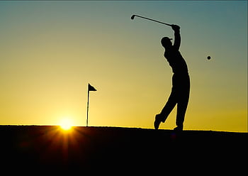 Silhouette of a golfer swinging at sunrise, capturing the essence of the sport. HD wallpaper