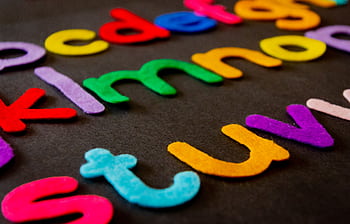 Bright and colorful felt alphabet letters arranged on a dark surface, perfect for educational and creative projects. HD wallpaper
