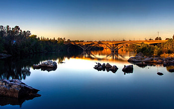 bridge over a calm river, river, trees, bridge, rocks, sunset HD wallpaper