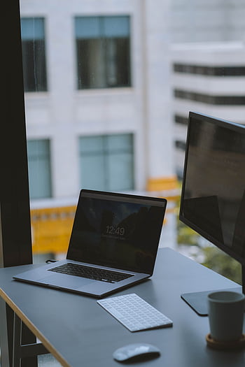Minimalist office desk with laptop, keyboard, and coffee cup by a large window. HD phone wallpaper