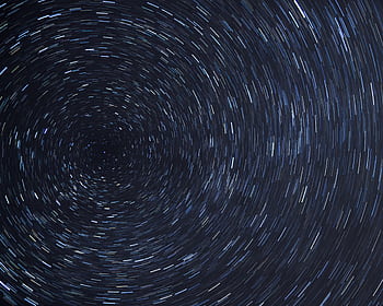 Dazzling star trails creating a spiral effect in the clear night sky. HD wallpaper