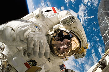 Astronaut floating in space during a spacewalk, visible Earth in the background. HD wallpaper