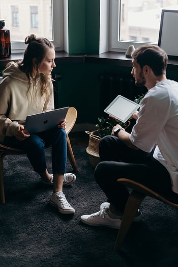 Two adults having a tech-focused discussion in a cozy home setting. HD phone wallpaper