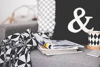 A cozy living room scene with magazines, a patterned mug, and decor elements on a couch. HD wallpaper