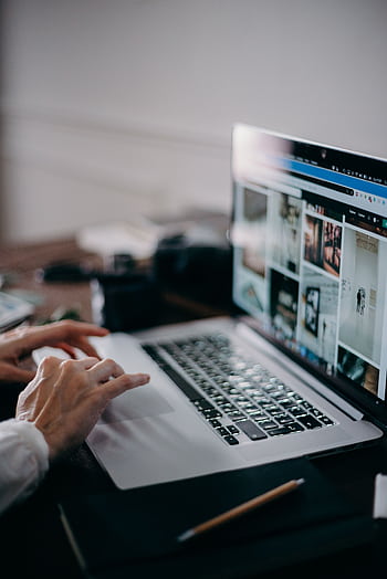A person working on a laptop browsing visual content in an indoor setting, capturing digital creativity and remote work. HD phone wallpaper