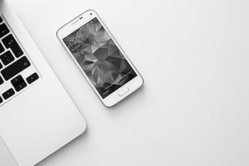 A minimalist office desk with a laptop and smart displaying a geometric . HD wallpaper
