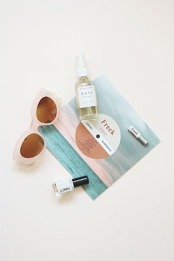 High-angle flatlay of summer essentials including sunglasses and skincare products. HD phone wallpaper