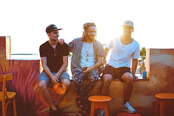 Three friends relax on a Tel Aviv rooftop, soaking up a vibrant sunset atmosphere. HD wallpaper