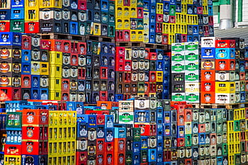 A vibrant display of beer crates stacked in a warehouse, showcasing various brands. HD wallpaper