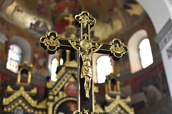 Close-up of a detailed gold crucifix in an elaborate church interior, symbolizing Christian faith and spirituality. HD wallpaper