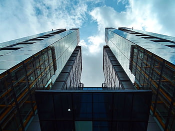 Low-angle view of sleek, modern skyscrapers with glass facades under a blue sky. HD wallpaper