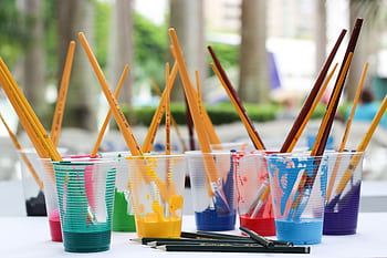 Vibrant paint brushes and pencils in plastic cups for arts and crafts. HD wallpaper
