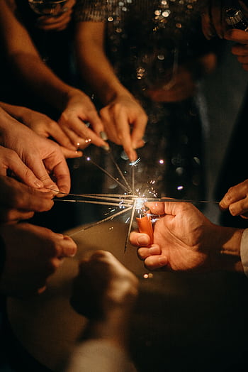 A group of people enjoying a festive celebration by lighting sparklers together. HD phone wallpaper