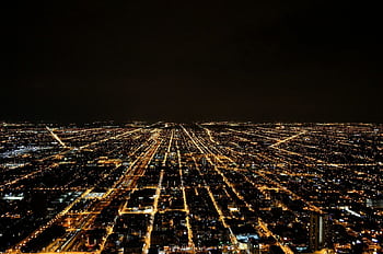 A breathtaking aerial view of a sprawling city illuminated by glowing lights against the night sky. HD wallpaper