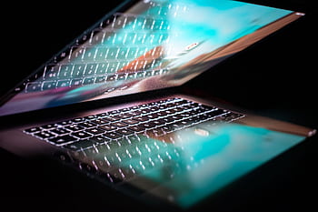 Close-up of a modern laptop with illuminated keyboard and colorful screen reflection. HD wallpaper