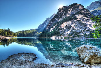 Serene mountain lake with crystal-clear reflections under a bright daytime sky. HD wallpaper