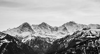 Black and white capturing majestic, snow-capped mountains in a serene winter landscape. HD wallpaper
