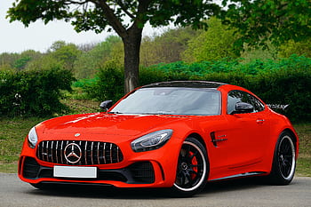 A stunning luxury red sports car parked on a scenic road in the UK. HD wallpaper