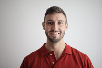 Headshot of a happy man with a beard wearing a red polo shirt against a white background. HD wallpaper