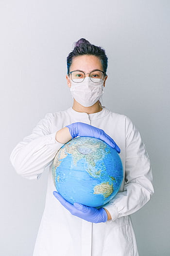 A medical professional wearing a mask and gloves holds a globe, symbolizing global health care during a pandemic. HD phone wallpaper