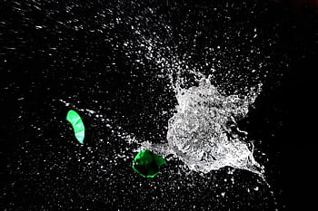 High-speed capture of a water balloon bursting, revealing dramatic splash against a dark background. HD wallpaper