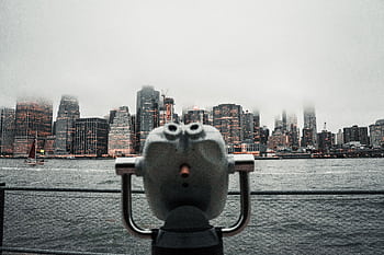 Dramatic view of New York City skyline shrouded in fog from a waterfront viewing deck. HD wallpaper