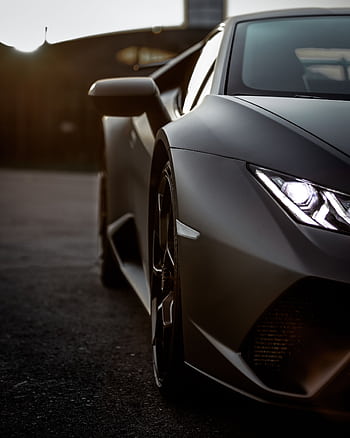 Close-up of a sleek Lamborghini supercar with headlights on, captured in Italy during sunset. HD phone wallpaper