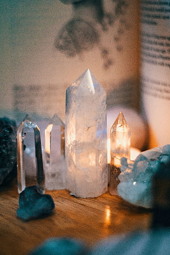 Beautiful quartz crystals displayed on a wooden table with warm ambient lighting. HD phone wallpaper