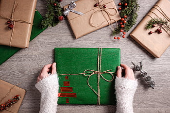 Top view of Christmas gifts wrapped in green and brown paper with festive decor. HD wallpaper