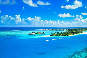 Aerial view of a luxurious tropical resort on a pristine island surrounded by azure waters and lush greenery. HD wallpaper