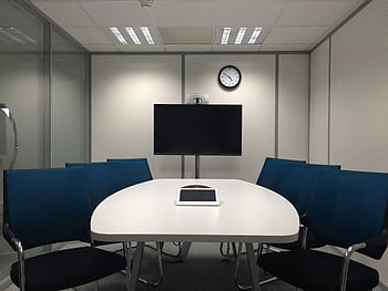 Sleek conference room with a table, chairs, TV, and video conferencing equipment. HD wallpaper